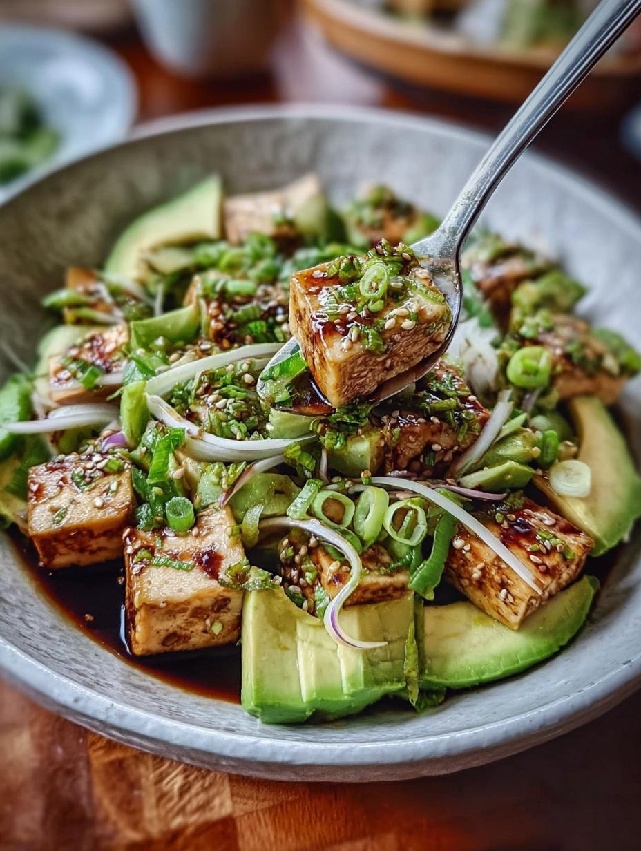 Close-up of a vibrant Tofu Avocado Salad with fresh scallions and a zesty dressing, showcasing its delicate textures and colors.